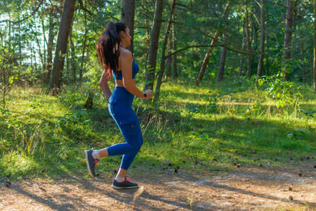 Pretty young girl runner jogging summer morning in the forest.Young pretty fitness woman running at...