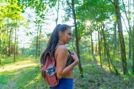 Young woman with backpack in a summer forest.Hiking at summertime evening.Outdoors shot.の写真素材