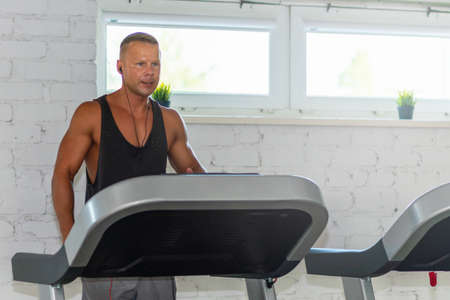 Young man in sportswear running on treadmill at gym.Handsome sport gym man running on the treadmill.Indoors shot.Man running in a gym on a treadmill.Exercising fitness.Healthy lifestyle concept.の写真素材