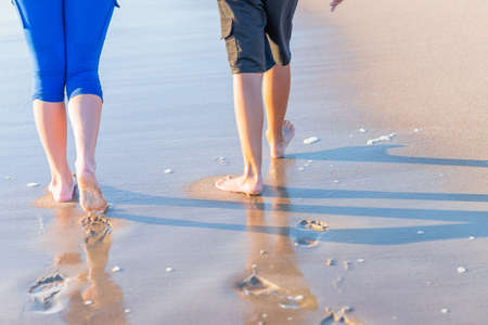 Mother and son walking along the beach. Legs, feet and footprints on the sand. feet of the mother and the boy walk along the beach. Selective focus.Summer vacation.Rear view.の写真素材