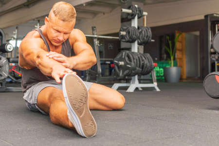 Man at the gym doing stretching exercises on the floor.Sports man at the gym doing stretching legs feet exercises.の写真素材