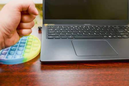 businessman hand nervous fist anti-stress toys pop-it on the keyboard. New popular silicone colorful...