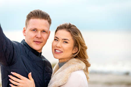 Beautiful young happy woman hugging,cuddle young boyfriend while taking selfie photo on sunny beach.Closeup.の写真素材