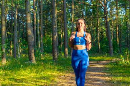 Young woman traveler with backpack walking in a summer forest, wanderlust travel concept,copy space.の写真素材