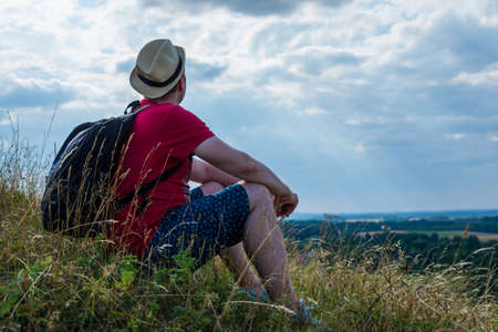 Young man admiring beautiful view of the forest landscape rear view.Young man standing alone summer day outdoor with wild forest on background. Travel Lifestyle concept back viewの写真素材