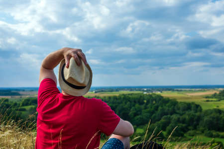 Young man admiring beautiful view of the forest landscape rear view.Young man standing alone summer day outdoor with wild forest on background. Travel Lifestyle concept back viewの写真素材