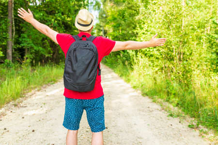 Caucasian male tourist in forest with his arms wide open. Copy space.Man backpacker arms outstretched in forest, freedom and active lifestyle concept.Summer day.の写真素材