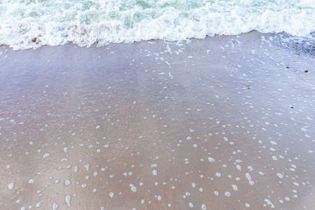 Soft wave of the sea on sandy beach white foam.Top view of a wave breaking on the sand at the beach.Top view,Copy space.の写真素材
