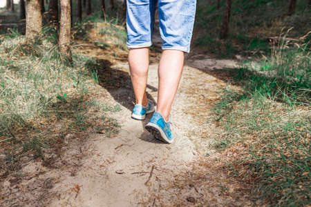 Man walking or running on path in forest summer natureo outdoors, sport shoes and exercising on fotpath.Closeup.の写真素材