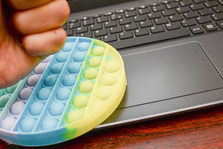 businessman hand nervous fist anti-stress toys pop-it on the keyboard. New popular silicone colorful anti-stress toy pop it for suppress the stress.の写真素材