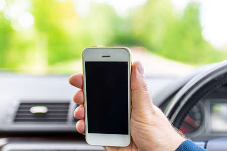 Mans hand hold and touch screen smart phone, blur on the road high way forest summer background.copy space,advertisement,banner,mockup.の写真素材