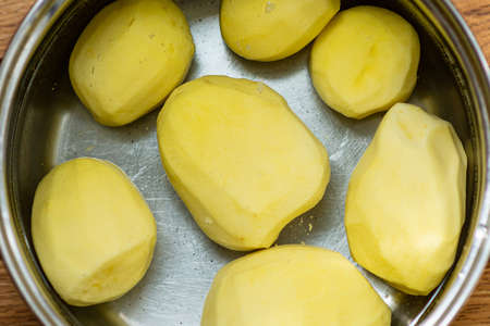 Peeled potatoes in a stainless pot of water.Potatoes peeled in water. Ingredients for soup.Raw potatoes peeled and cut for boiling or roasting shot top view,closeup.の写真素材