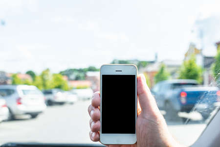 Man using phone in car, GPS navigation ,blank space frame on smartphone in hand with blur image of traffic jam as background.Man using cell phone while driving.の写真素材