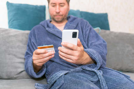 Young man buying fashion items through the Internet on cellphone by using credit card.Online...
