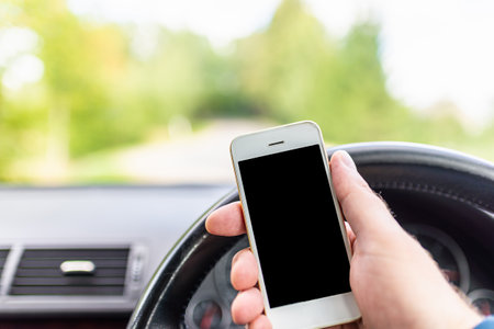 Mans hand hold and touch screen smart phone, blur on the road high way forest summer background.copy space,advertisement,banner,mockup.の写真素材
