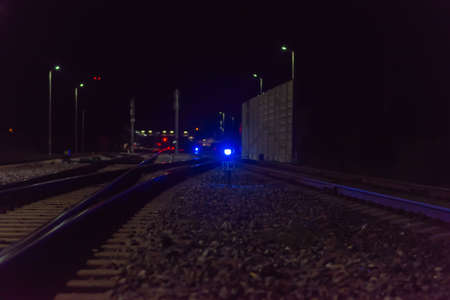 Night empty railroad tracks near train station with lights in dark night.A train station near railway.Photo from railway.Selective focus.の写真素材