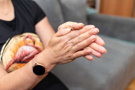 Womans hands applying moisturizer on her skin. Female smears hand cream at home, closeup.hands with a leaving cosmetic cream for a youth and elasticity of a skin. personal care. minimalism concept.の写真素材