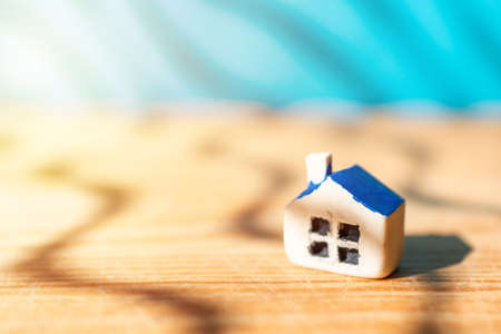 One miniature toy house on a wooden table on a sunlight.Yellow house model blurred blue background.Copy space.Closeup.の写真素材
