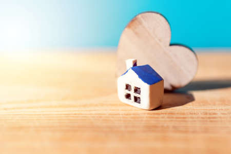 Toy House wooden heart on a wooden and blue blurred sun background.Copy space.Selective focus.の写真素材