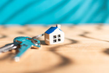 Miniature new house with house keys on wooden blue blurred background, real estate and property business concept.Closeup,selective focus.の写真素材