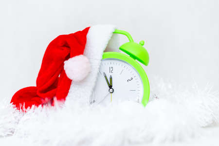 Alarm clock with Santa hat and Christmas decorations isolated on gray white background.New Year 2022 concept.の写真素材