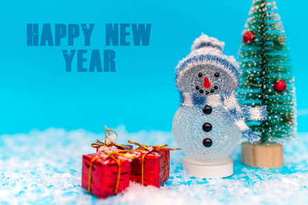 Happy New Year inscription snowman on a blue background with presents.Front view image.の写真素材