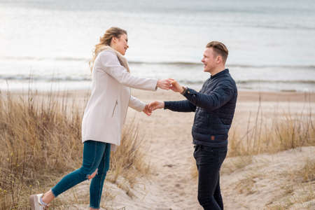 happy couple having fun on the beach.young hipster couple playing on a spring sea.spring,autumn vacation.の写真素材