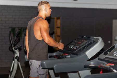 Young man in sportswear running on treadmill at gym.Handsome sport gym man running on the treadmill.Indoors shot.Man running in a gym on a treadmill.Exercising fitness.Healthy lifestyle concept.の写真素材
