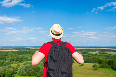 Young man admiring beautiful view of the forest landscape rear view.Young man standing alone summer day outdoor with wild forest on background. Travel Lifestyle concept back viewの写真素材
