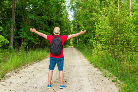 Caucasian male tourist in forest with his arms wide open. Copy space.Man backpacker arms outstretched in forest, freedom and active lifestyle concept.Summer day.の写真素材