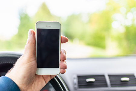 Mans hand hold and touch screen smart phone, blur on the road high way forest summer background.copy space,advertisement,banner,mockup.の写真素材