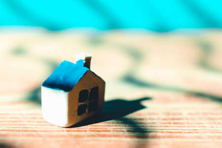 One miniature toy house on a wooden table. Yellow house model blurred blue background.Copy space.Closeup.Toned.の写真素材