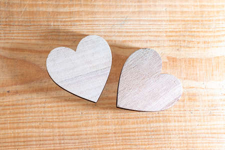 Two wooden handmade hearts placed on a brown wood board.Valentines day concept. Two hearts flat lay on wooden background. Greeting card concept. Top view. Copy space.Top view.の写真素材