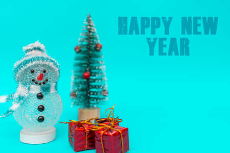 Happy New Year inscription toy snowman on a blue background with presents.Front view image.の写真素材