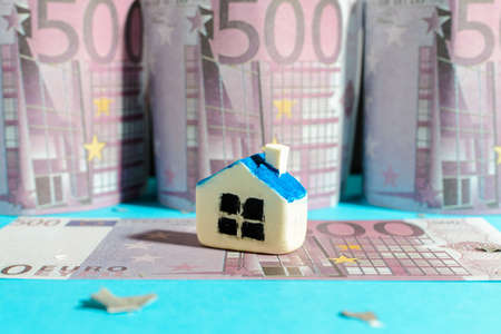Miniature toy house stand on 500 Euro bill banknotes.Buy or rent a house concept.close-up.Blurred five hundred cash background.の写真素材