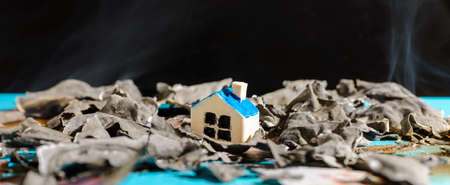 Miniature toy house stand on burnt money Euro bill banknotes.Banner,close up.Blurred long exposure background and foreground.Indoors shot.の写真素材