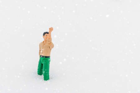 Miniature toy man holding something, white snow background.copy space.Outdoors shot.