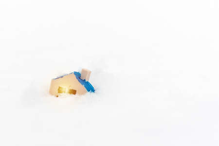 Miniature toy house on the snowdrift.business disaster,natural disaster,Home insurance concept.Copy space.の写真素材