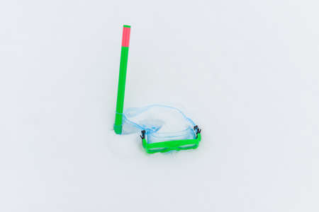 Snow fun. Green diving goggles,snorkel on white snow.Scuba snorkeling green diving set flat lay on the snow at cold winter day.Diving equipment.Copy space.の写真素材