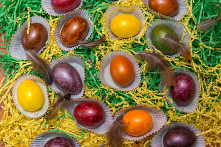 Many colorful easter eggs from above on a heap.Top view.chicken feathers lying down on the eggs.の写真素材