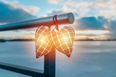 Couple two hearts shines on the cloudy blurred background against winter evening landscape.の写真素材