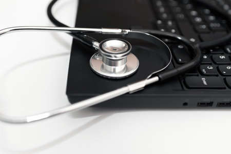 Doctor workplace with a stethoscope and laptop.Medical technology background, selective focus on doctor's stethoscope and laptop computer ,black and white. online health, telemedicine concept.Close upの写真素材