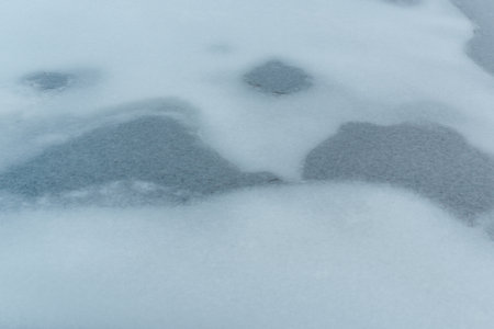 Frozen water.Blue ice frozen lake with snow and cracks at winter. Melting ice on the lake, spring.Close up.の写真素材