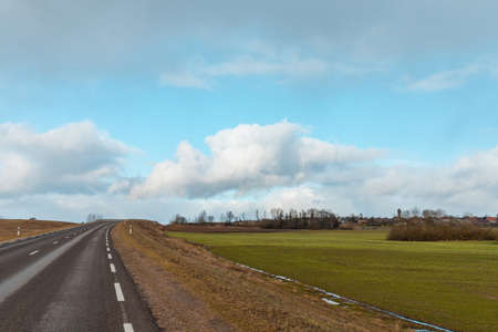 Empty road asphalt landscape among green spring meadows , blue sky,white clouds.の写真素材