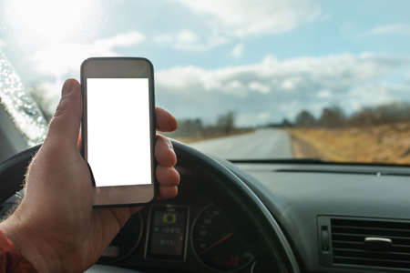 Man using blank white screen mobile smartphone inside a car in spring day landscape. copy space for...