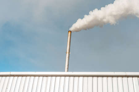 Pipe and smoke.Polluting air with white smoke from industrial chimney outdoors. CO2 emissions.Copy space.の写真素材