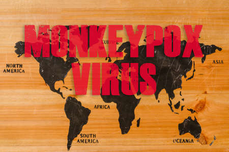 Monkeypox outbreak concept. Monkeypox is caused by monkeypox virus. Smallpox is a viral zoonotic disease. Virus transmitted to humans from animals.Inscription on the world wooden map.の写真素材