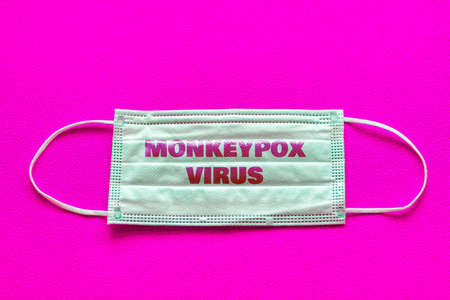 Monkeypox outbreak concept.Inscription monkeypox virus on medical face mask.Virus transmitted to humans from animals.Pink background.の写真素材