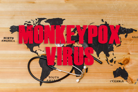 Inscription world wooden map,a stethoscope and a magnifying lip lie on the map.Monkeypox is caused by monkeypox virus.Smallpox is a viral zoonotic disease. Virus transmitted to humans from animals.の写真素材