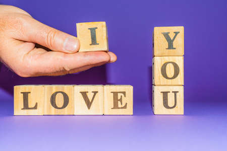 Male palm holding letter-i, love you text on wooden blocks purple veri peri background.copy space.の写真素材